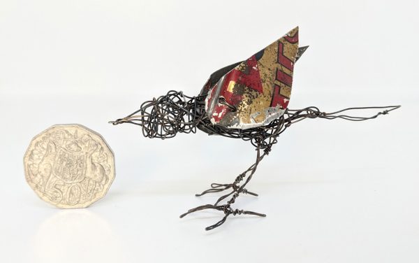 Wire sculpture of bird next to fifty cent coin